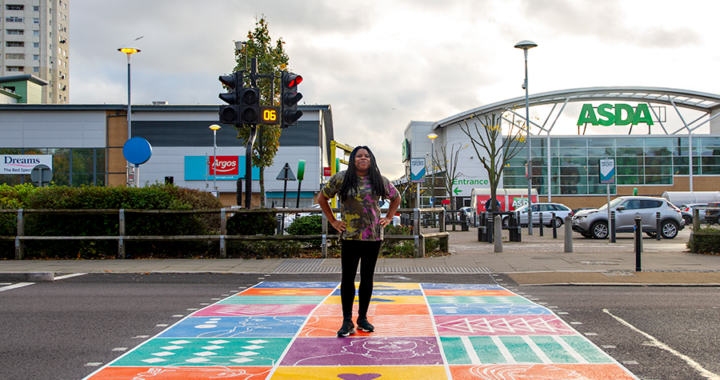 Photo of Kareen Cox standing on the colourful crossing in edmonton green designed by Kareen Cox