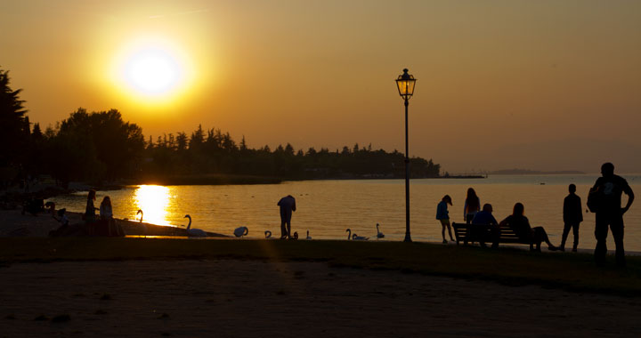 Sunset taken in Lake Garda. Water and people walking alongside the promenade